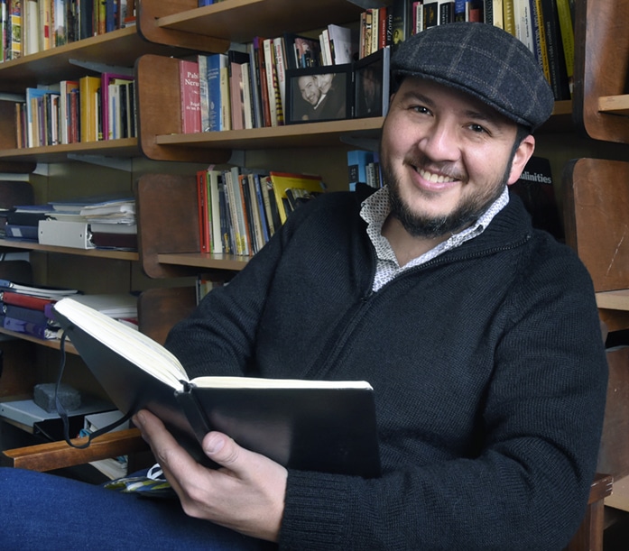 Oswaldo Estrada, holding his notebook, in his office in Dey Hall.