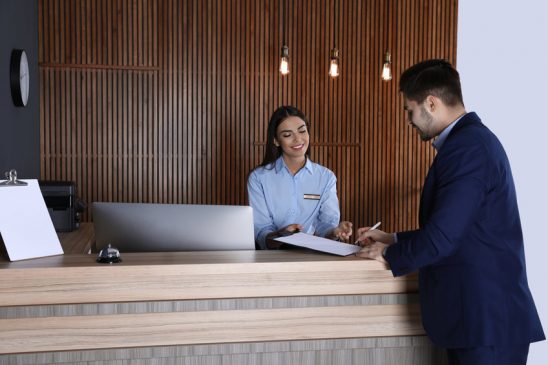 Receptionist registering client at desk in lobby